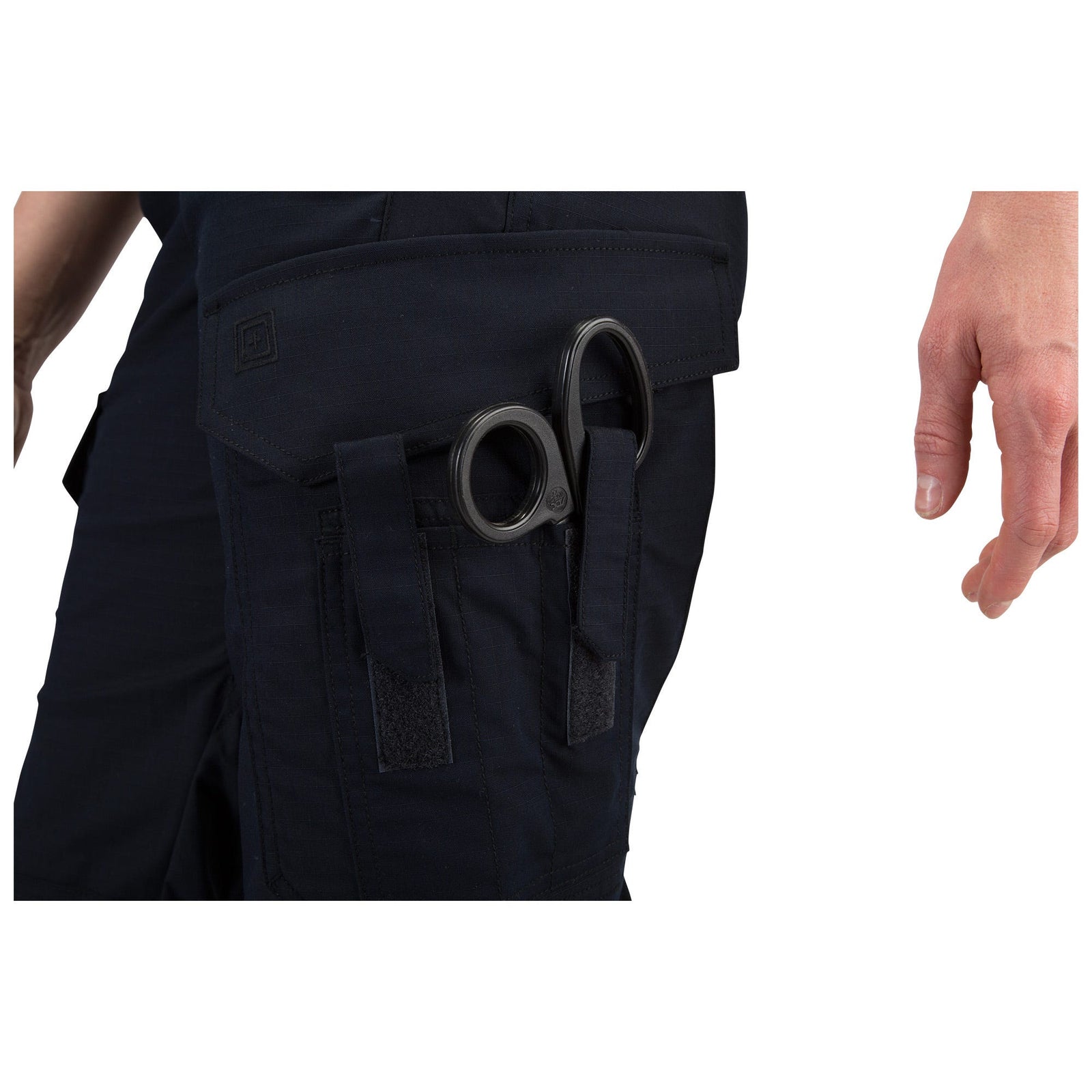 Black tactical pants with a pocket containing a pair of scissors on a white background