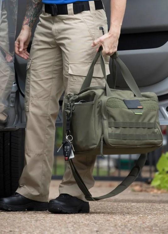 Person holding a green duffel bag next to a vehicle