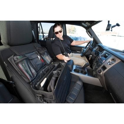 Person sitting in a car with a large black bag on the passenger seat