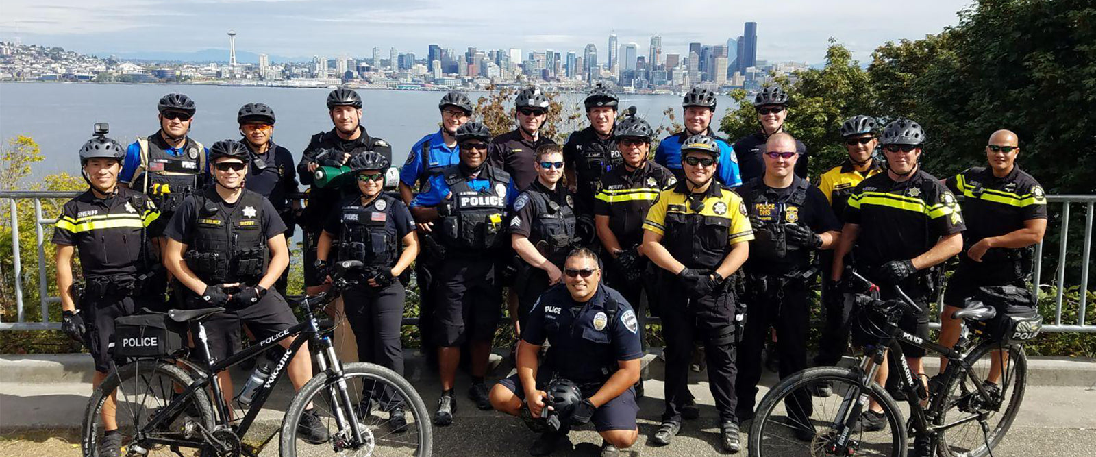 Group of police officers with bicycles in front of a city skyline