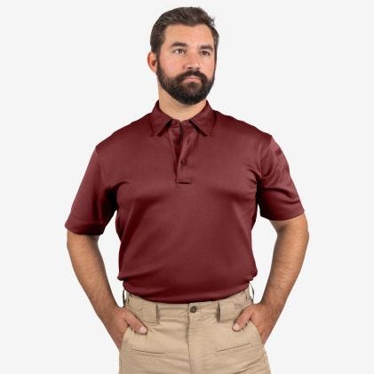Man wearing a maroon polo shirt and beige pants on a white background