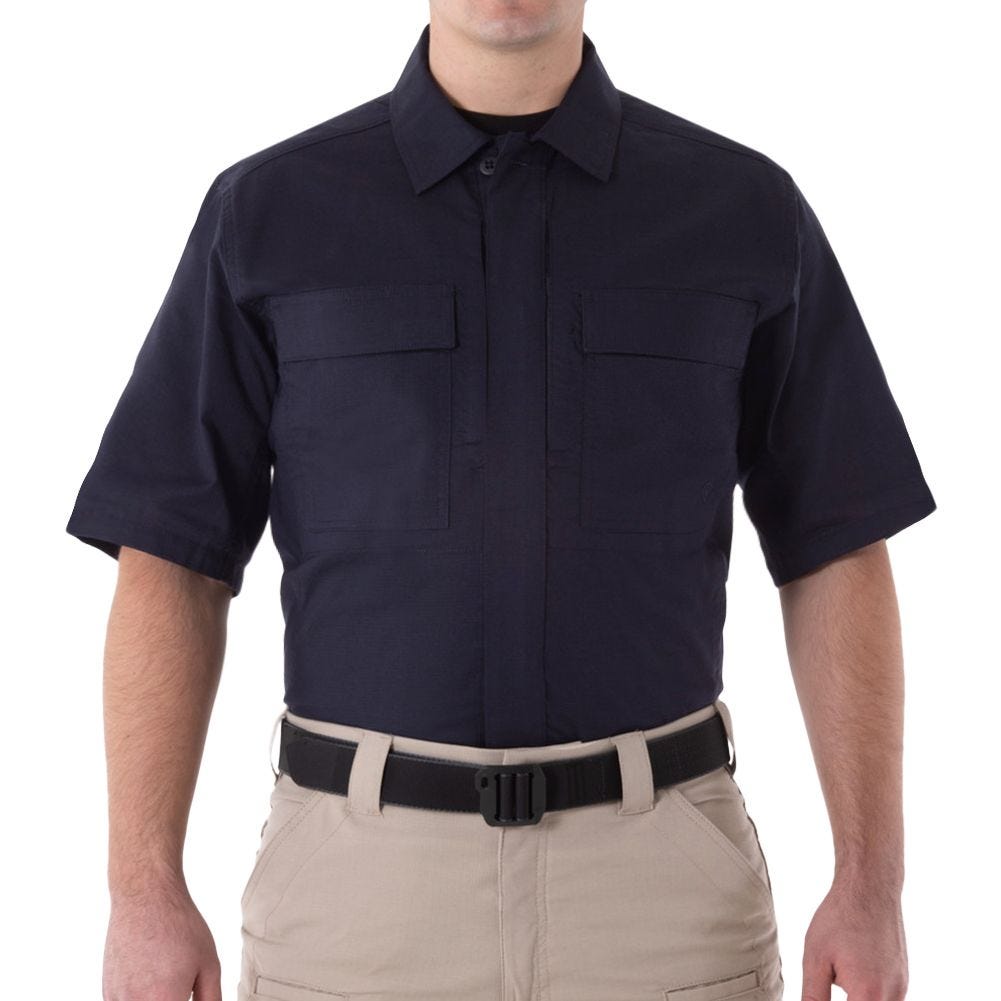 Person wearing a navy short-sleeve shirt and beige pants on a white background