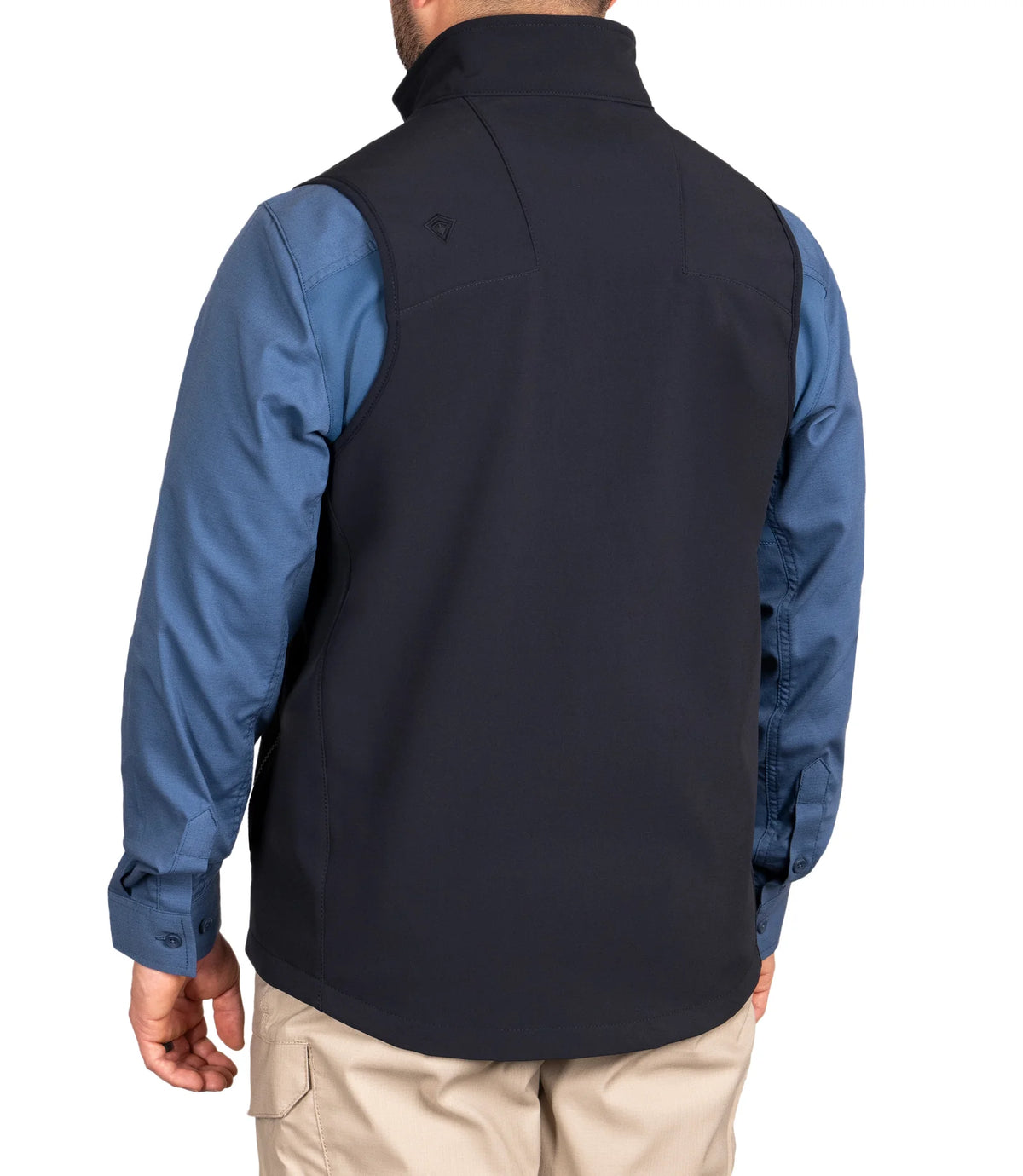 Person wearing a navy vest over a blue shirt on a white background