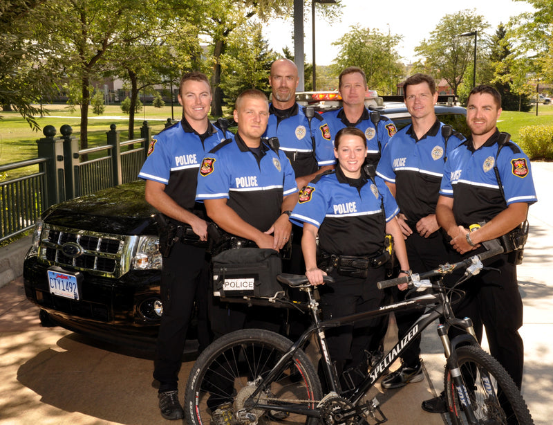 Group of police officers posing with a bicycle in a park setting