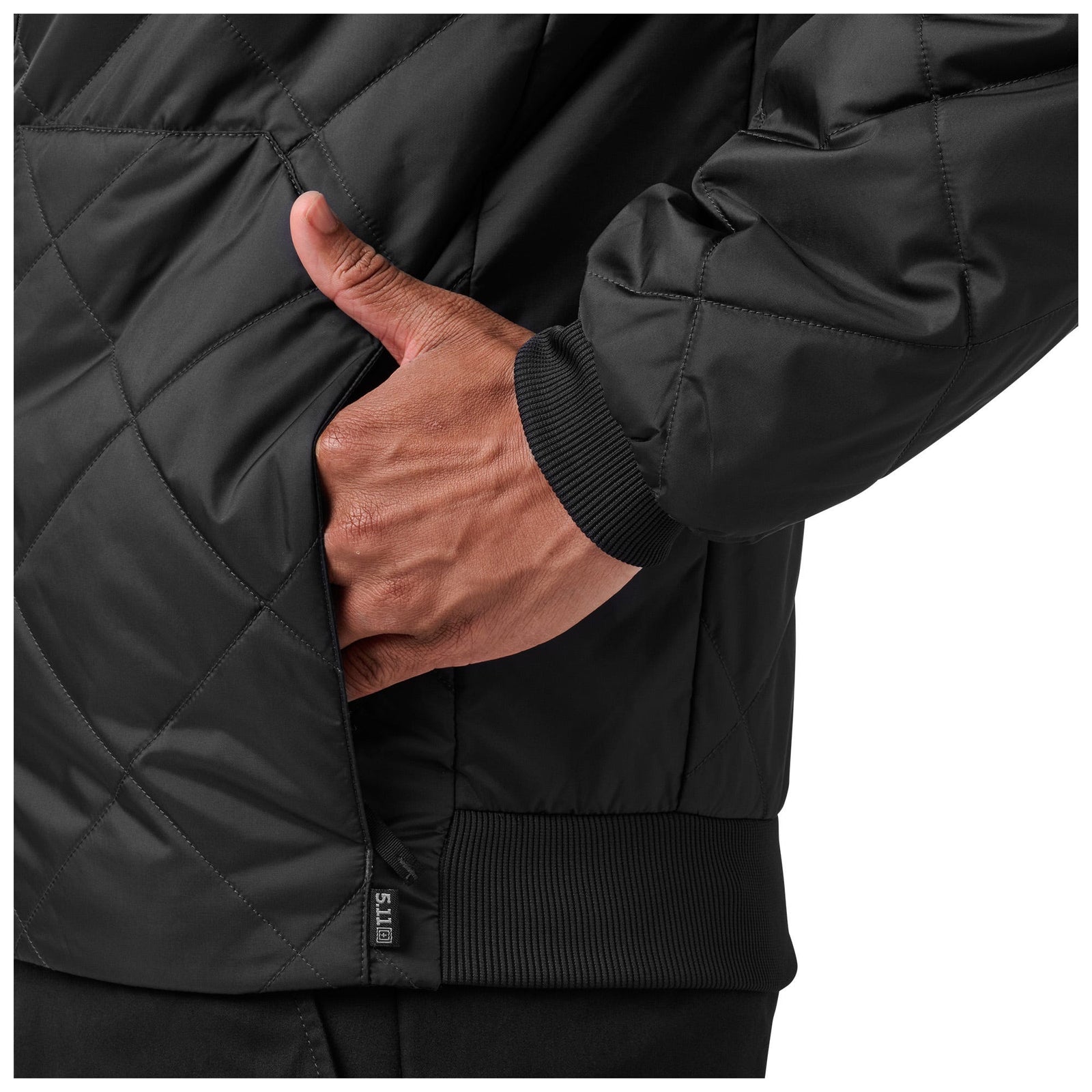 Close-up of a person wearing a black quilted jacket with a hand in the pocket.