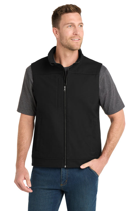 Man wearing a black vest over a gray shirt with blue jeans on a white background