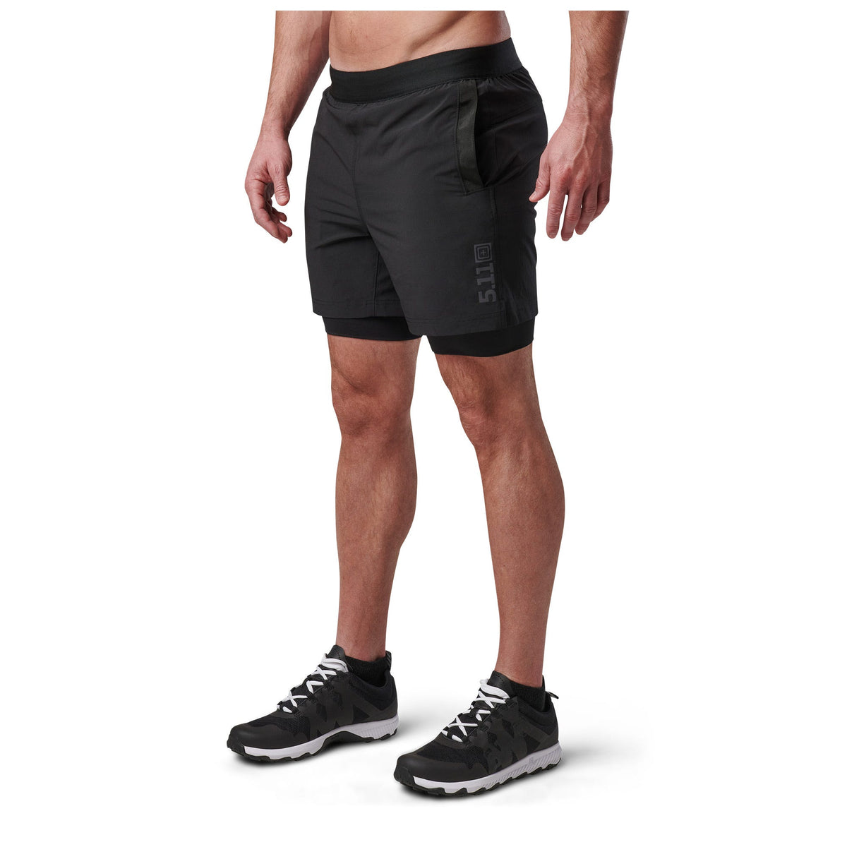 Person wearing black athletic shorts and shoes on a white background