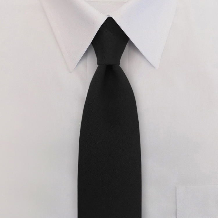 Black tie worn with a white dress shirt on a light gray background