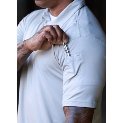 Person wearing a light-colored shirt with a pocket detail, focusing on the shirt and arm.