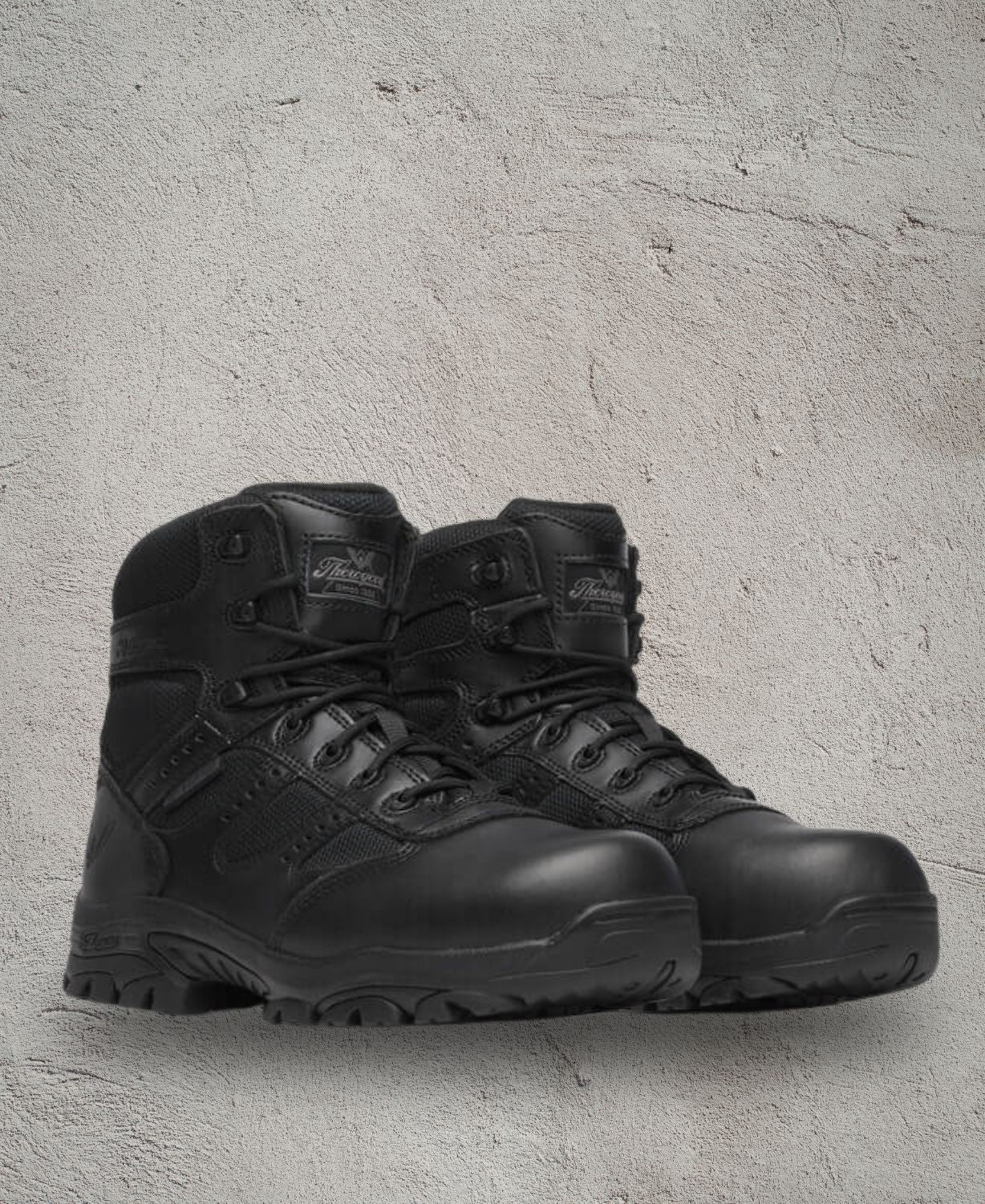 Pair of black tactical boots on a textured gray background
