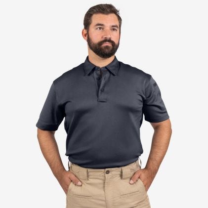Man wearing a black polo shirt and beige pants on a white background