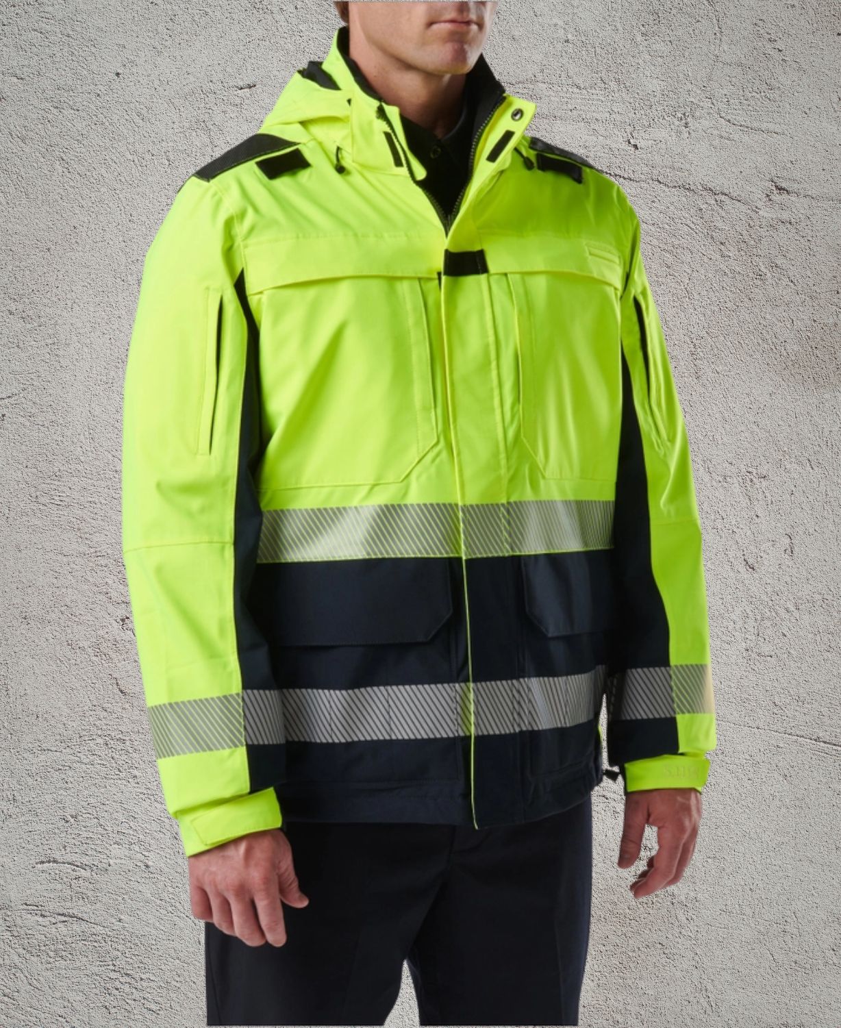 Person wearing a high-visibility jacket with reflective stripes on a gray background