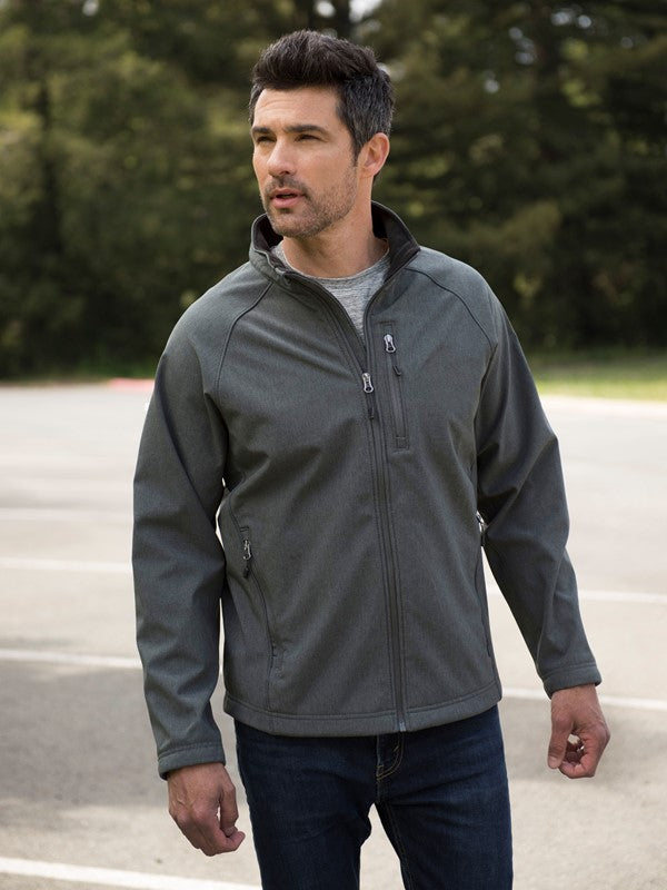 Man wearing a gray jacket outdoors with trees in the background